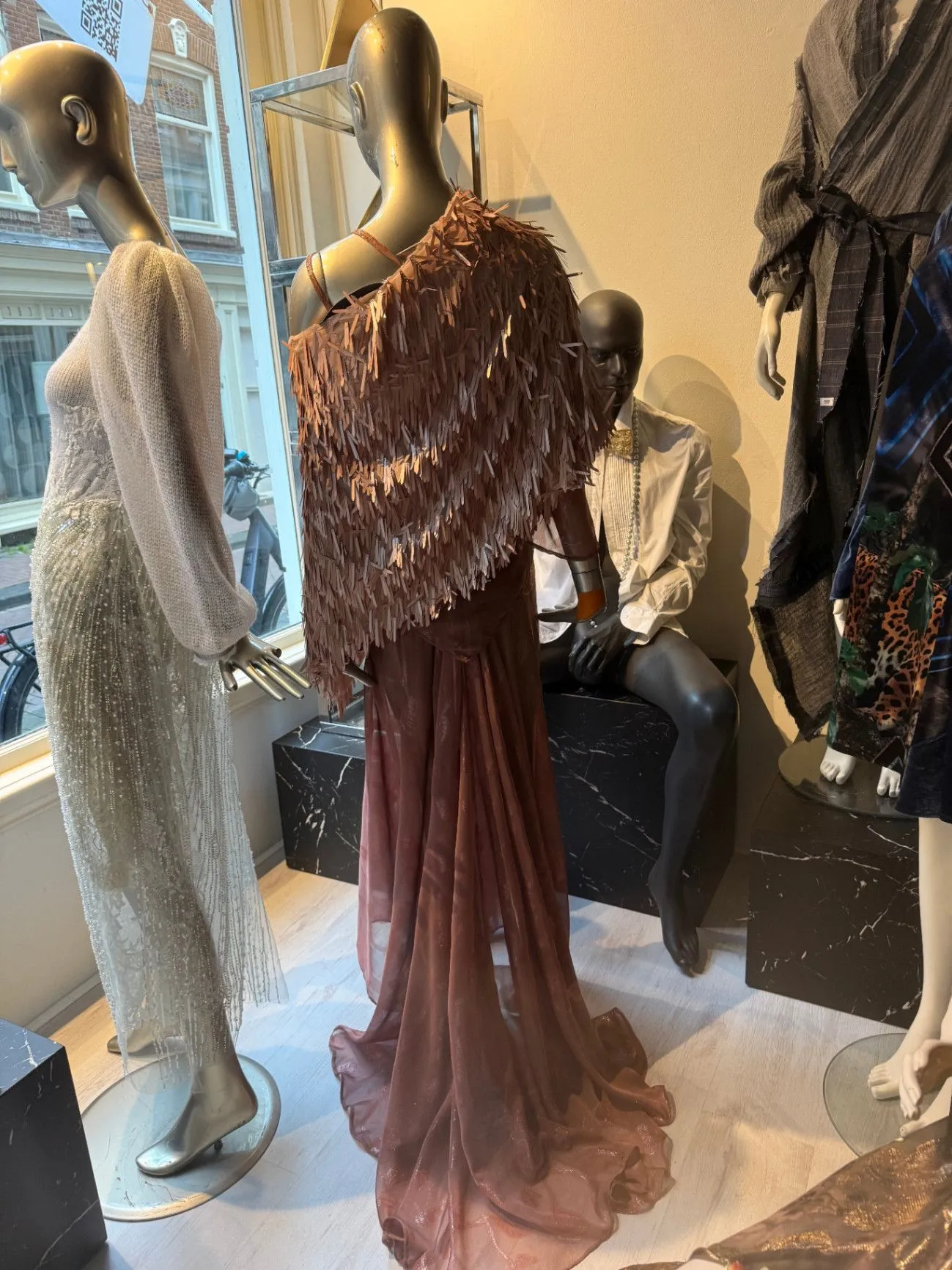 Atelier store-window display: fringed cape over a blush gown